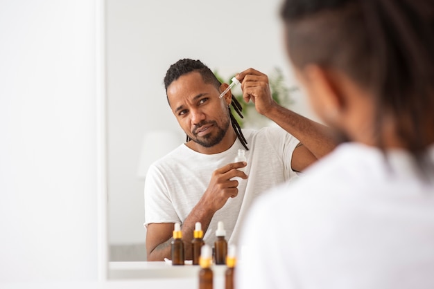 Free photo close up man applying serum bottle