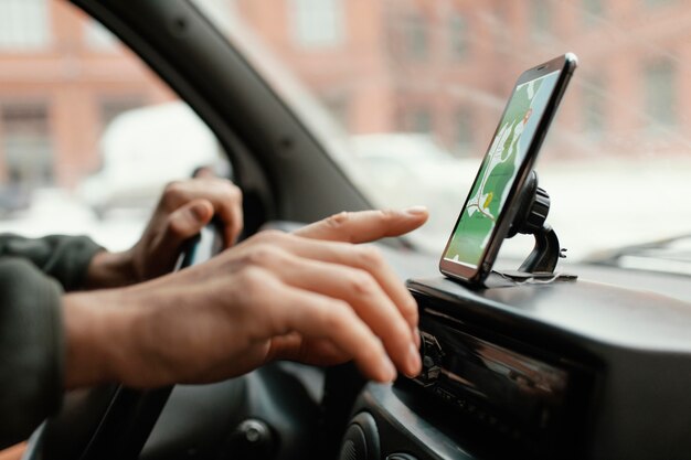 Крупным планом человек в машине с картой на мобильном телефоне