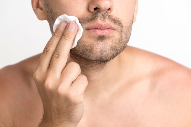 Close-up of man cleaning face with cotton pad