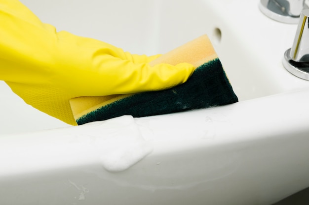 Free photo close up man cleaning sink with sponge