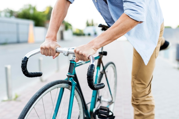 Close-up man climbing his bicycle