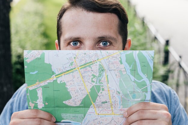 Close-up of man covering his mouth with map