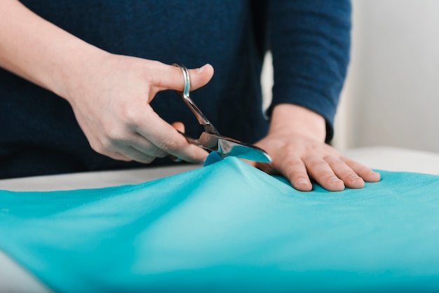 Close-up of man cutting blue fabric