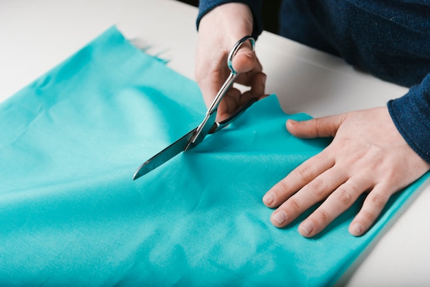 Close-up of man cutting blue material