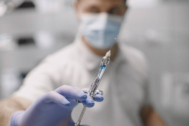 남자 치과 의사의 클로즈업 통증 완화 주사에 대 한 마취의 전체 주사기와 장갑에 손을. 예방 및 건강 관리 개념