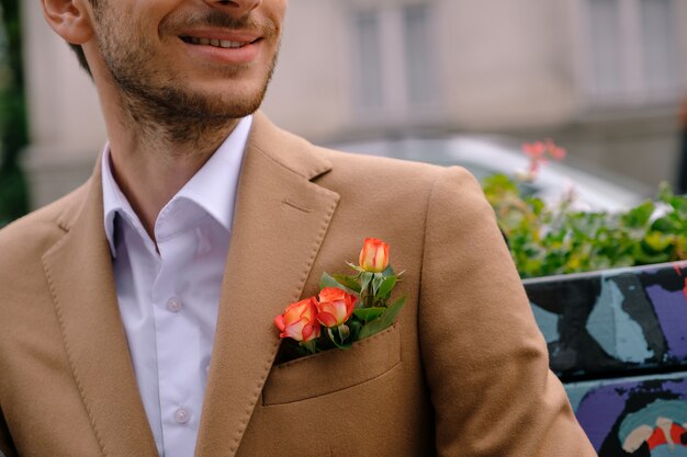 Close-up man dressed in classy jaket with three roses in poket