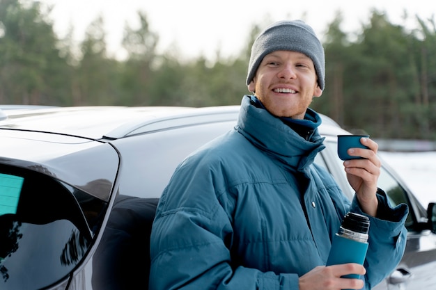 Крупным планом мужчина наслаждается горячим напитком во время зимней поездки