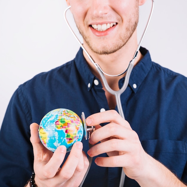 Close-up of a man examining globe with stethoscope