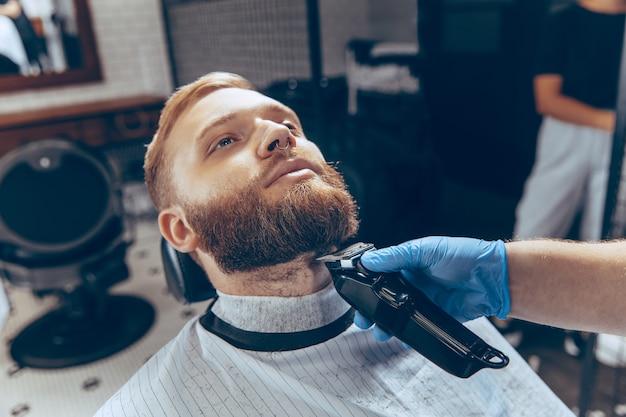 Крупным планом - мужчина, стригущийся в парикмахерской в маске во время пандемии коронавируса.