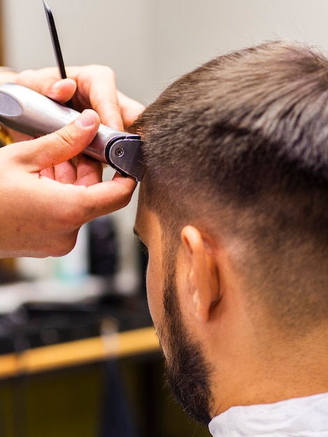 Uomo del primo piano che ottiene i suoi capelli tagliati da dietro