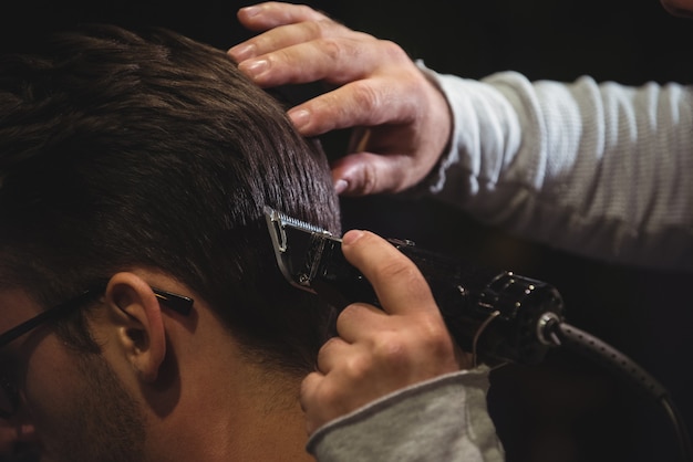 Foto gratuita primo piano dell'uomo che ottiene i suoi capelli tagliati con il rifinitore