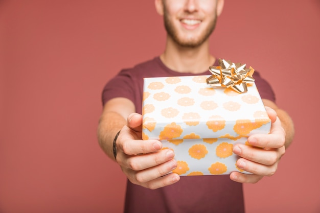 Foto gratuita primo piano dell'uomo che dà il contenitore di regalo con l'arco dorato