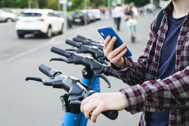 Close up of man hand using mobile app for rental electric scooter