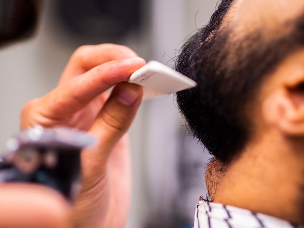 Close-up of man having his beard combed