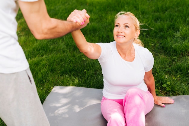 Close-up man helping woman to get up