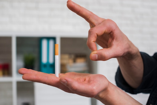 그의 손가락을 통해 담배를 명 중하는 사람의 근접 촬영