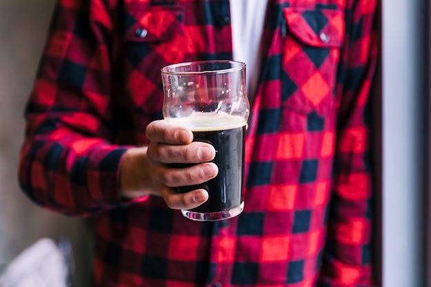 Foto gratuita primo piano di uomo che tiene il bicchiere di birra in mano