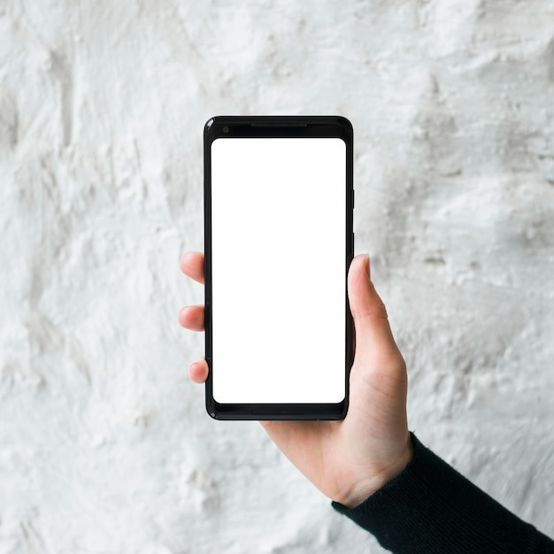 Крупным планом мужчина держит пустой экран смартфона на белом бетонную стену