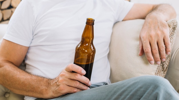 Primo piano di un uomo che tiene la bottiglia di birra