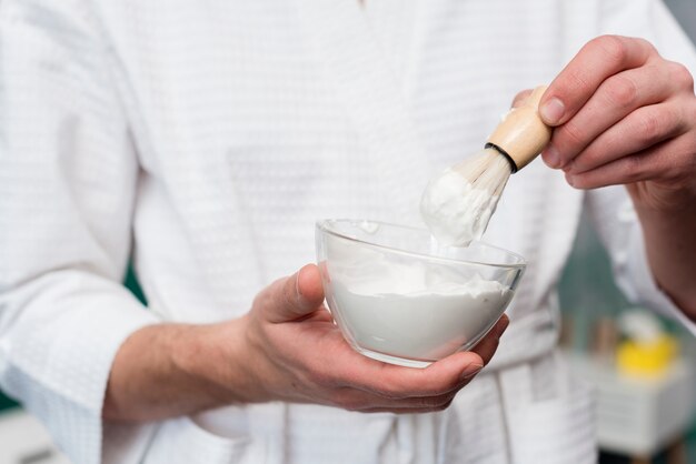 Close-up of man holding bowl of shaving foam