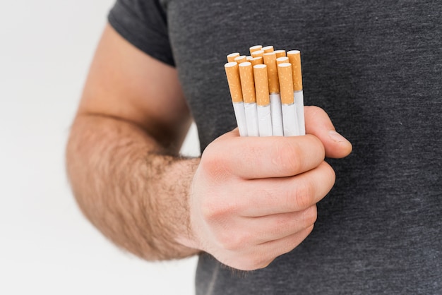 Close-up of a man holding bundle of cigarette isolated on white background