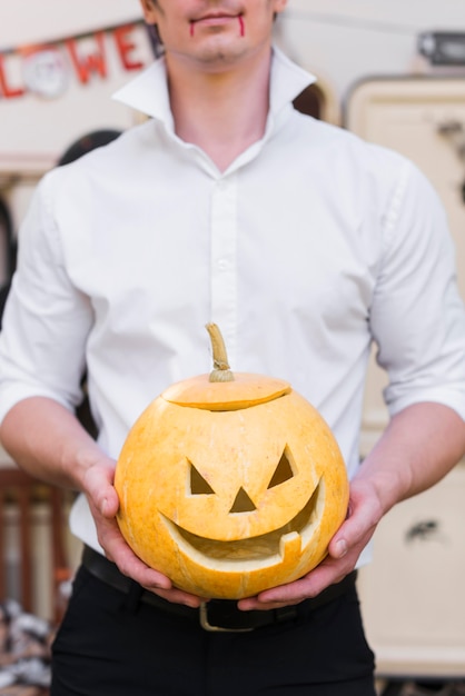 Free photo close-up man holding carved pumpkin