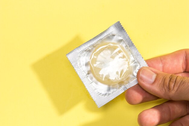 Close-up man holding a condom