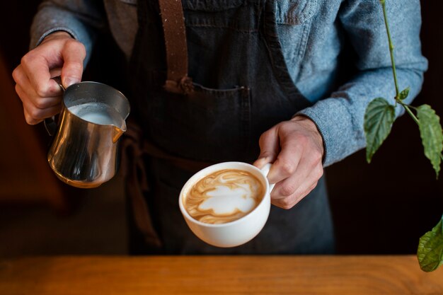 牛乳とコーヒーのカップを保持している男のクローズアップ