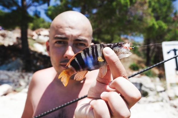 Foto gratuita primo piano di un uomo che tiene il pesce pescato fresco