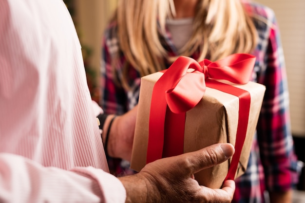 Close-up of man holding a gift with red bow