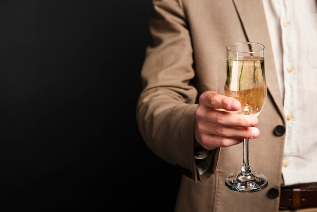 Close-up of man holding glass of champagne with copy-space