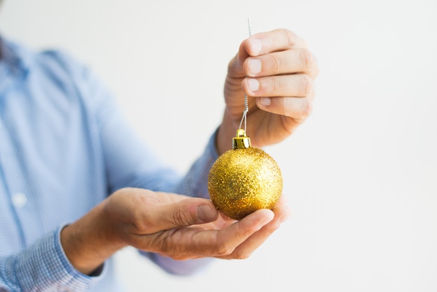 Close-up of man holding glittering Christmas ball