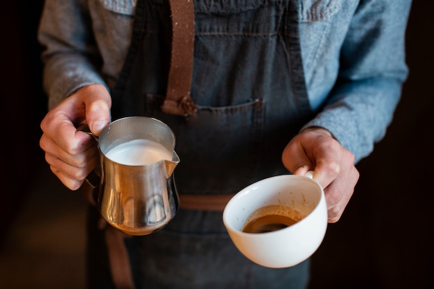 Foto gratuita primo piano del latte e della tazza di caffè della tenuta dell'uomo