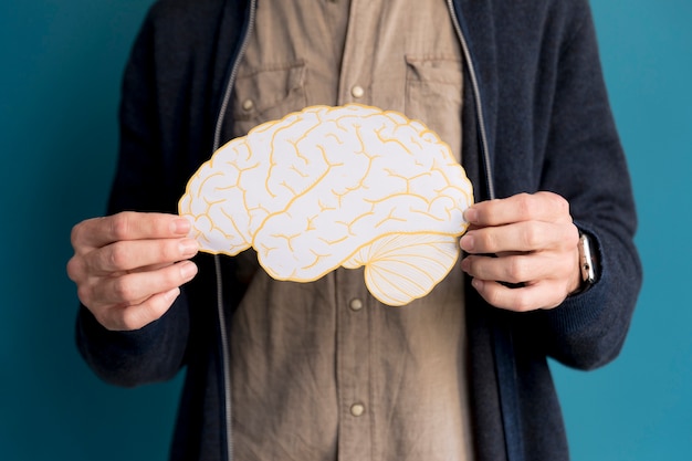 Бесплатное фото Мужчина крупным планом держит бумажный мозг