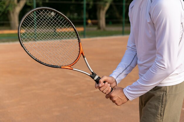 Крупным планом мужчина держит теннисную ракетку