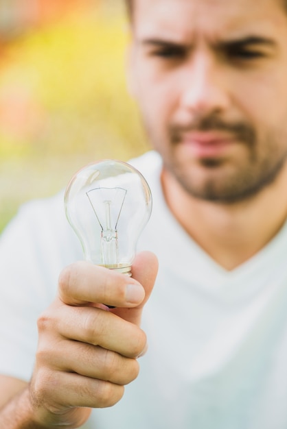 Close-up of man holding transparent light bulb