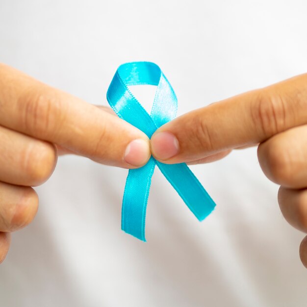 Close-up man holding up blue ribbon