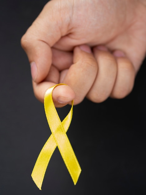 Close-up man holding up golden ribbon