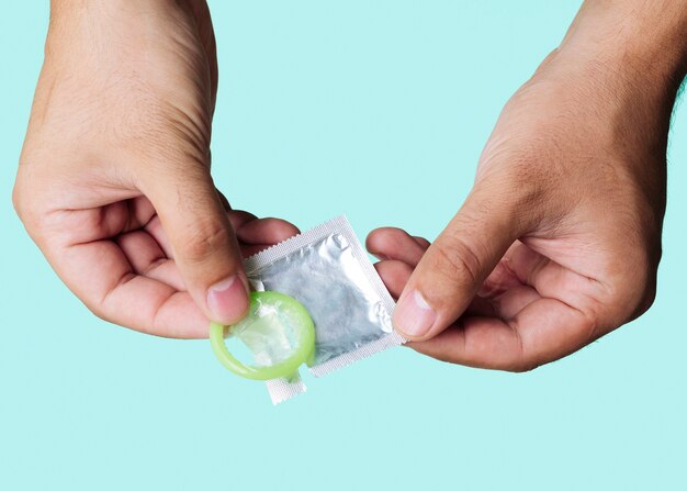 Close-up man holding up green condom