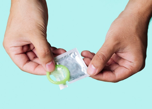 Крупным планом мужчина держит зеленый презерватив