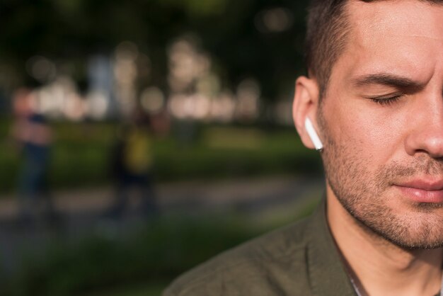 close-up of man listening music with wireless earphone