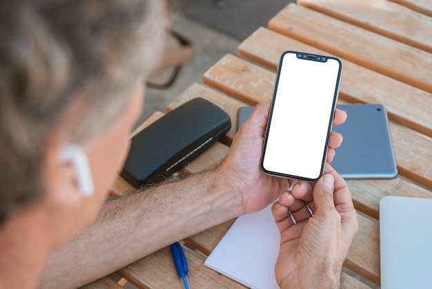 空の白い画面で携帯電話を見ている男のクローズアップ