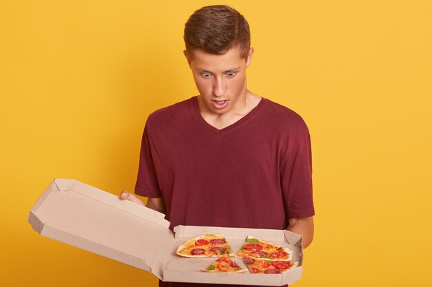 Close up of man looking at pizza with opened mouth and astonished facial expression