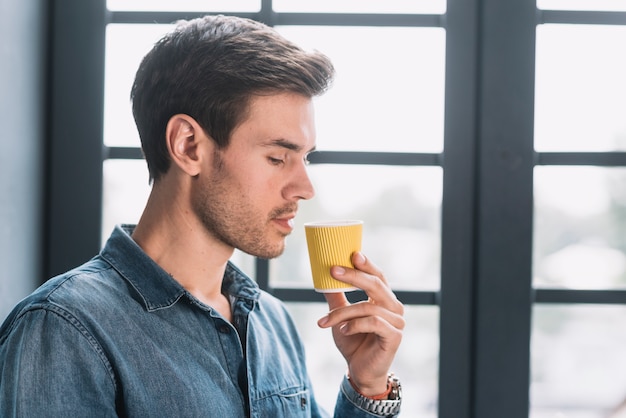 Close-up of a man looking at take away coffee cup in hand