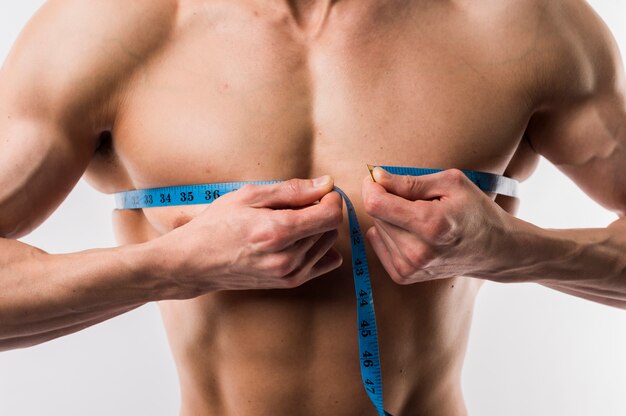 Close-up of man measuring muscled chest