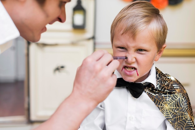 Close-up man painting kid's face