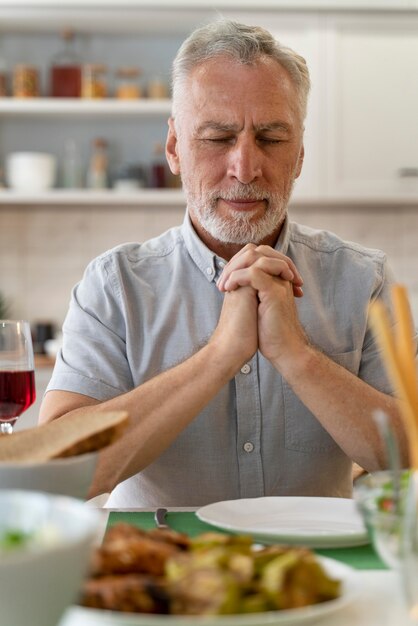 Close up on man parying before dinner with family