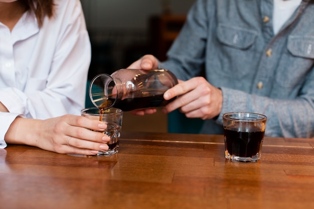 Close-up of man pouring coffee in cup for woman