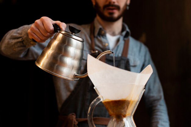 Primo piano del caffè di versamento dell'uomo dalla pentola in filtro