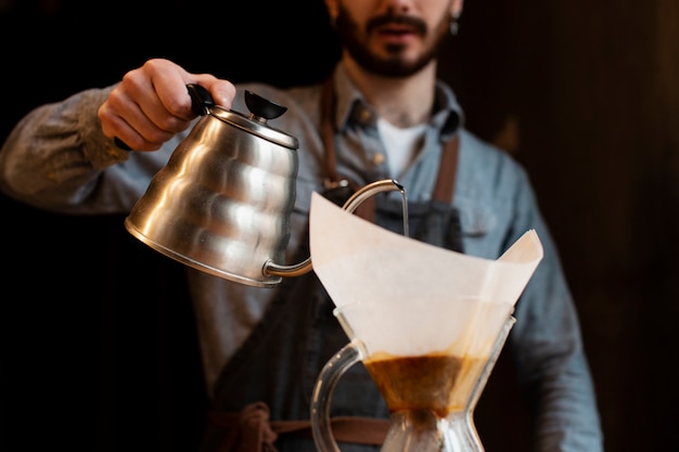 Close-up of man pouring coffee from pot in filter